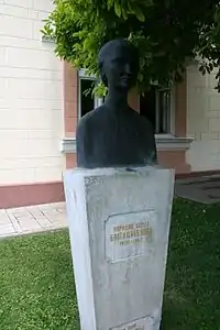 Memorial stone with gold inscription and a blackbust on top of it.