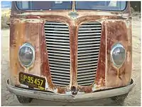 Front end with grill, emblem, and teardrop headlights