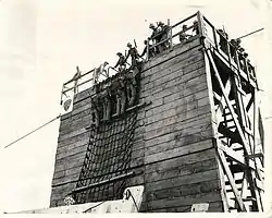 Marines climbing down cargo net into landing craft.