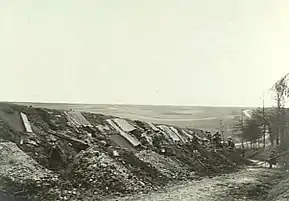 a black and white photograph of positions dug into the side of a sunken road, with soldiers resting