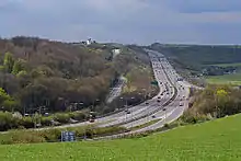 long-distance view with woods and fields and a four-lane road curving through it