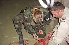 Image 23US Military Police officer restraining and sedating prisoner, while a soldier holds him down (from Political corruption)