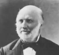 balck and white photograph of a balding man wearing a suit with bowtie, in a tight headshot