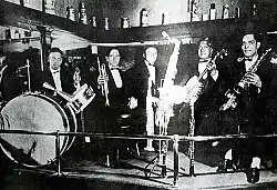 Barbarin, left, plays drums with a band on Rampart Street in New Orleans, 1919. Also pictured are (left to right): Arnold Metoyer, trumpet; Luis Russel, piano; Willie Santiago, banjo; Albert Nicholas, saxophones and clarinet.