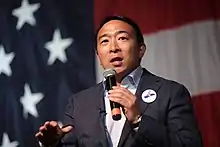 Yang holding a microphone while making a speech.