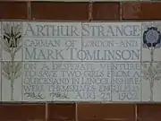 A tablet formed of five tiles of varying sizes, bordered by yellow and blue flowers in an art nouveau style