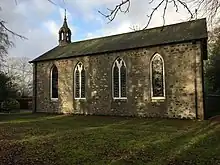 The south face of the church, containing four mosaic windows and a belfry on top of the church to the left.