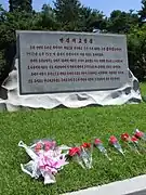 Sign about Kim's birthplace with flowers in front of it (2012)