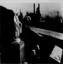 A black-and-white image of the shrine in 1957. There is no protective alcove around the statue as in later years. In the background there is the Penn-Lincoln Parkway.