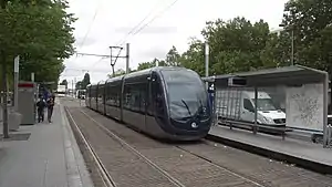 Double-track railway line with side platforms and blue-and-silver tram