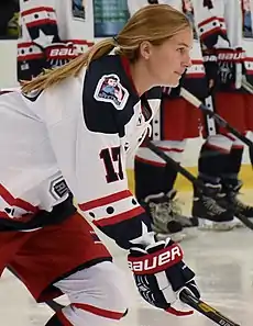 Bray Ketchum in ice hockey gear with team members standing behind her