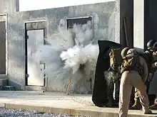 Marines covered behind a blast blanket during a breach