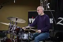 Man playing a drumset at a clinic session.