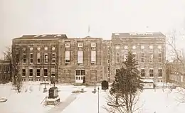 A sepia-toned photograph of a large, rectangular building.