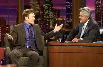 Late night talk show host Conan O'Brien is being interviewed by fellow host Jay Leno