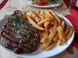 A rib steak, grilled in a griddleand served with French fries