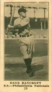 A sepia-toned baseball card of a player swinging his bat at a pitch.