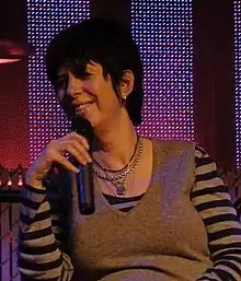 Diane Warren holding a mic.