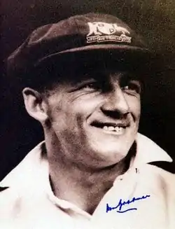 Donald Bradman wearing a black shirt and a dark cap