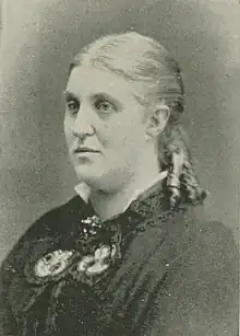 B&W portrait photo of a woman with her hair pulled back, wearing a dark blouse