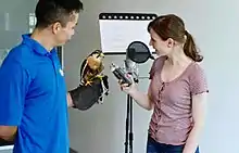 Actress recording podcast in microphone with Earth Rangers handler holding a bird to record vocals