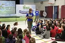 Earth Rangers presenter showing elementary students a tegu