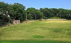 Sunken athletic field with a fieldstone retaining wall and hut