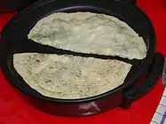 The filled and sealed pastries being cooked over a sac griddle until they become golden brown.