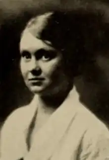 A young white woman wearing a white blouse or jacket with a collar