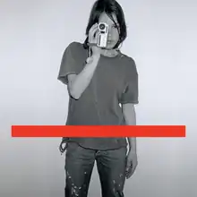 A black-and-white photo of a woman taking a photo with a red line.