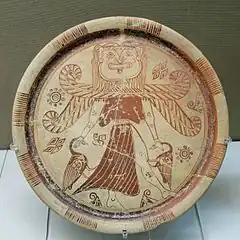 Representation of Potnia Theron with a Gorgon's head. Winged goddess wearing a split skirt and holding a bird in each hand, orientalizing plate, ca 600 BC, from Kameiros, Rhodes, British Museum, London.