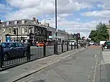 A 19th-century public house building and shops behind a road and pavement