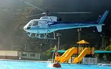 A Eurocopter Ecureuil dips its bucket into a swimming pool before returning to drop the water on a wildfire outside Naples, Italy