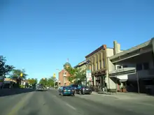 A road travels through a Main Street, with wall-to-wall buildings under a blue sky