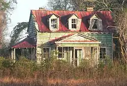 Ruins of a wooden two-storey house with a porch and a conservatory