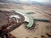 Tilted aerial view of modern airport. Aircraft are parked next to "arms" that extend from the central building