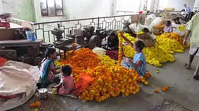 Flower-garland makers working next to decaying machine tools kept for parts on the first floor