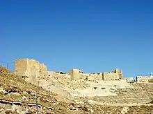 Ruined walls of a castle made of stone on a hill.