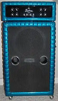 A 1970s era amplifier unit sitting on top of a large bass speaker cabinet. The speaker cabinet contains two fifteen-inch loudspeakers.