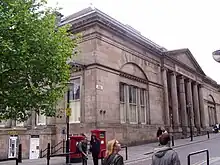 A neoclassical building seen from an angle, with a portico fronted by five columns