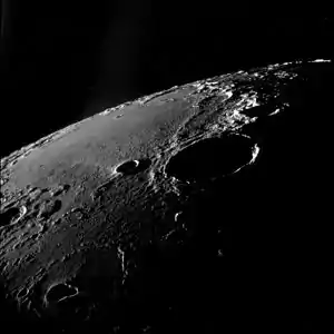 Oblique view facing southeast, from Apollo 11.  The large crater right of center is Theophilus, and Mädler is to its left.  Fracastorius is near the central horizon, and the white mountain on the horizon at right is part of the Rupes Altai.  The teardrop-shaped crater in the lower left is Torricelli.