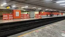 Passengers are waiting for the arrival of a train on a platform.