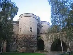 Low angle shot from the former moat now grassed over looking up at twin stone towers with an arched bridge accessing entrance to the right