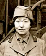 A white woman wearing glasses and a military-style uniform with cap