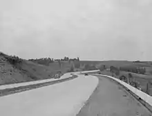 Black-and-white photo of four-lane highway, with one car in each direction