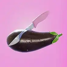 An eggplant being cut by a knife on a pink background.