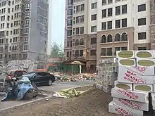 Taitou apartment exterior walls with cladding being removed by workers on cranes