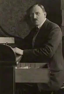 A man wearing a suit sitting at a writing desk