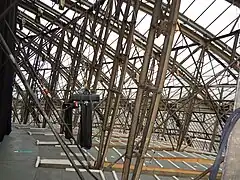 The glazed roof and vertical struts supporting the fluted aluminium ceiling, beneath the wooden floor