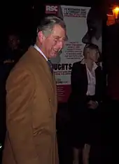 Charles in a brown coat attending a performance of Henry V in Stratford-upon-Avon